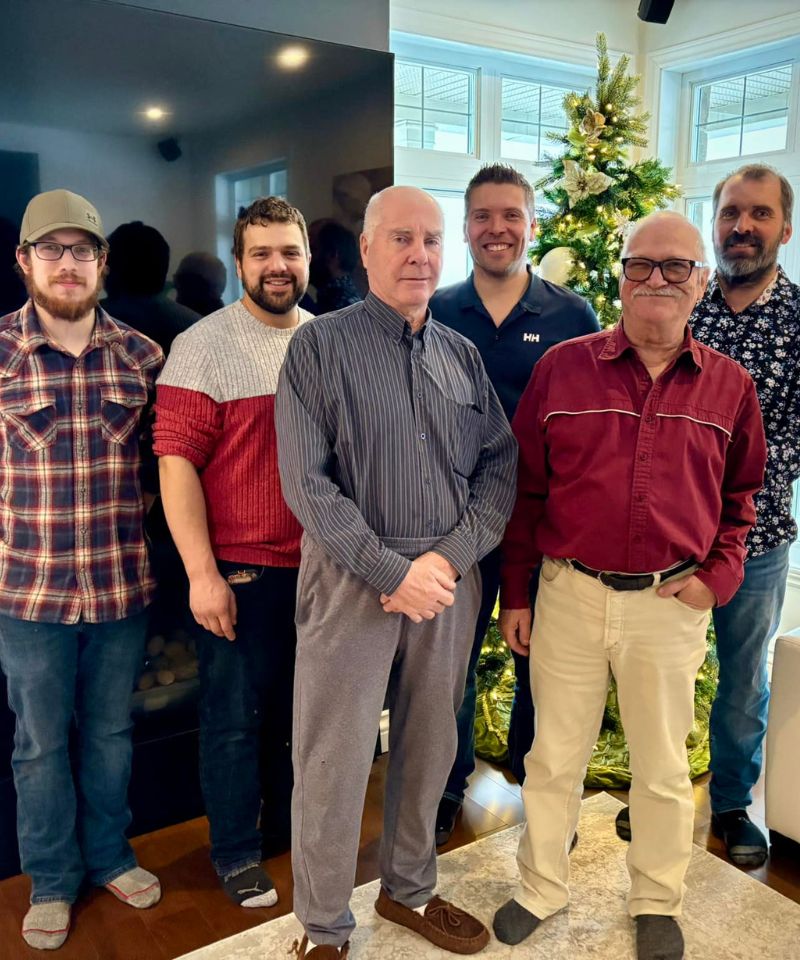 Équipe familiale du Garage André Plante & Fils posant devant un sapin de Noël à Saint-Évariste-de-Forsyth.